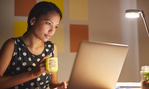 A woman holding a mug looking at a computer